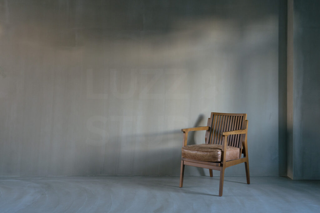 大阪のレンタル撮影スタジオ。グレーの塗り壁が広がる無機質な空間に、ヴィンテージ風のレザーチェアを配したモダンな撮影エリア