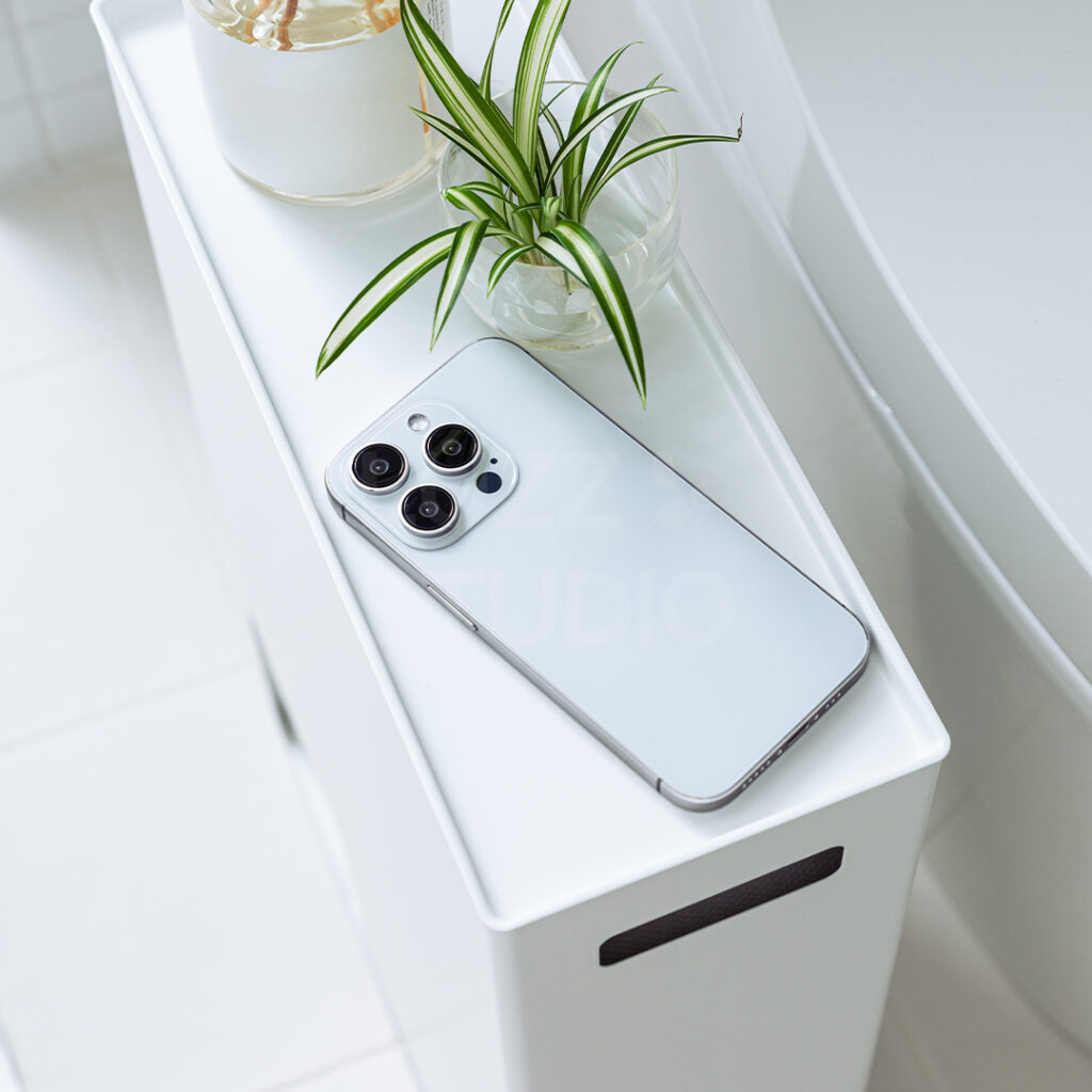 トイレットペーパーホルダーにスマホ、観葉植物、芳香剤が置かれている