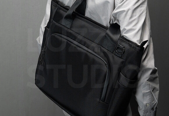 ガジェットバッグ（ビジネスバッグ）のEC販促商品撮影：グレー背景の室内でポーズをとる男性モデル