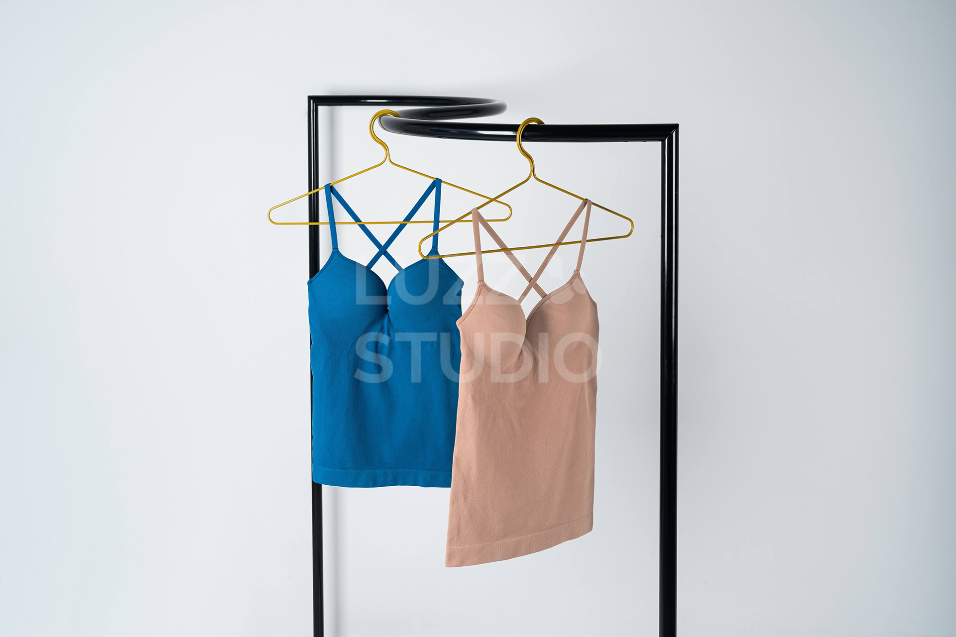 S字の特徴的なハンガーラックにベージュとブルーのブラトップキャンみそーるが陳列されている商品撮影写真。カーブによる視覚効果で一目で気になる画像に仕上げている。