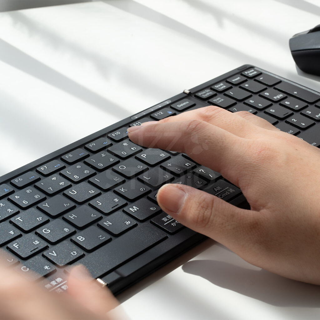 ECサイト・カタログ用:ガジェット機器(折り畳みキーボード)を使用している手の商品撮影写真