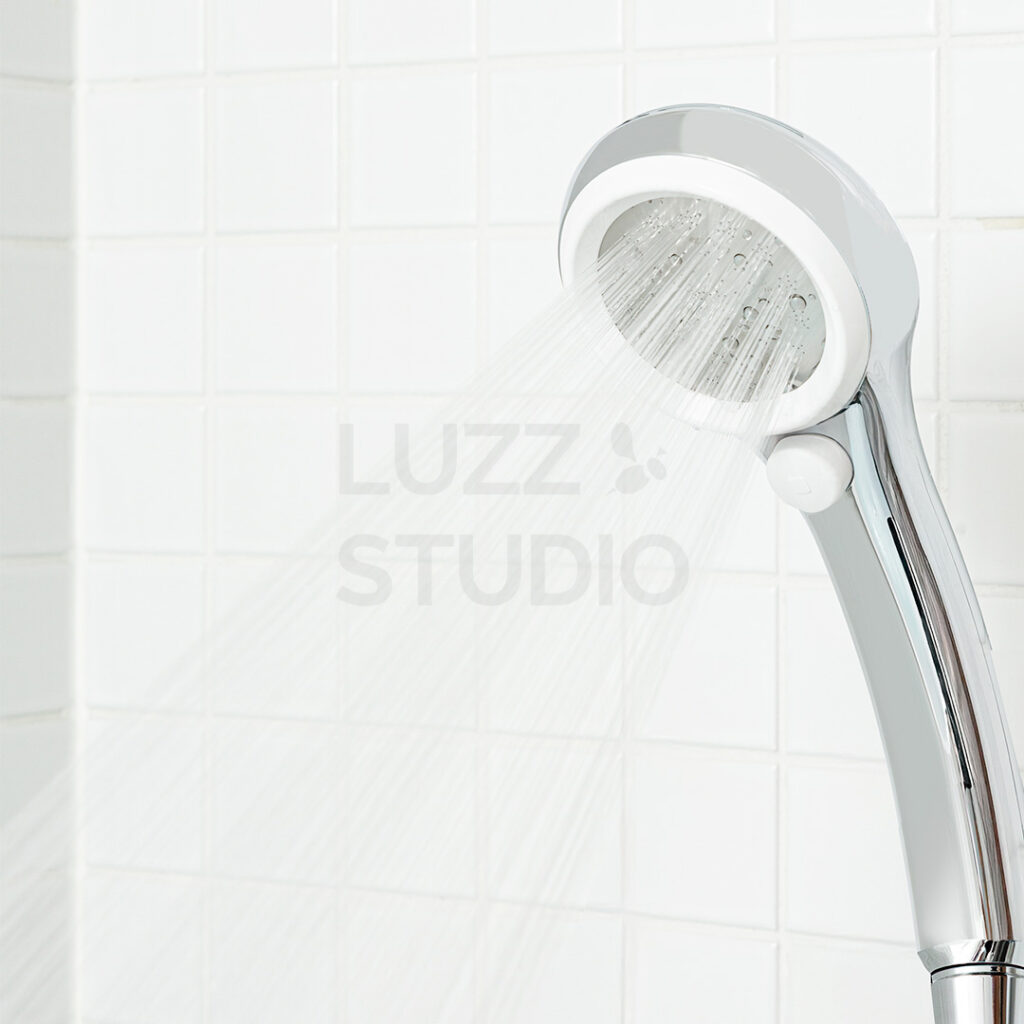 商品撮影:白いタイルの浴室で水が噴射しているシャワーヘッド