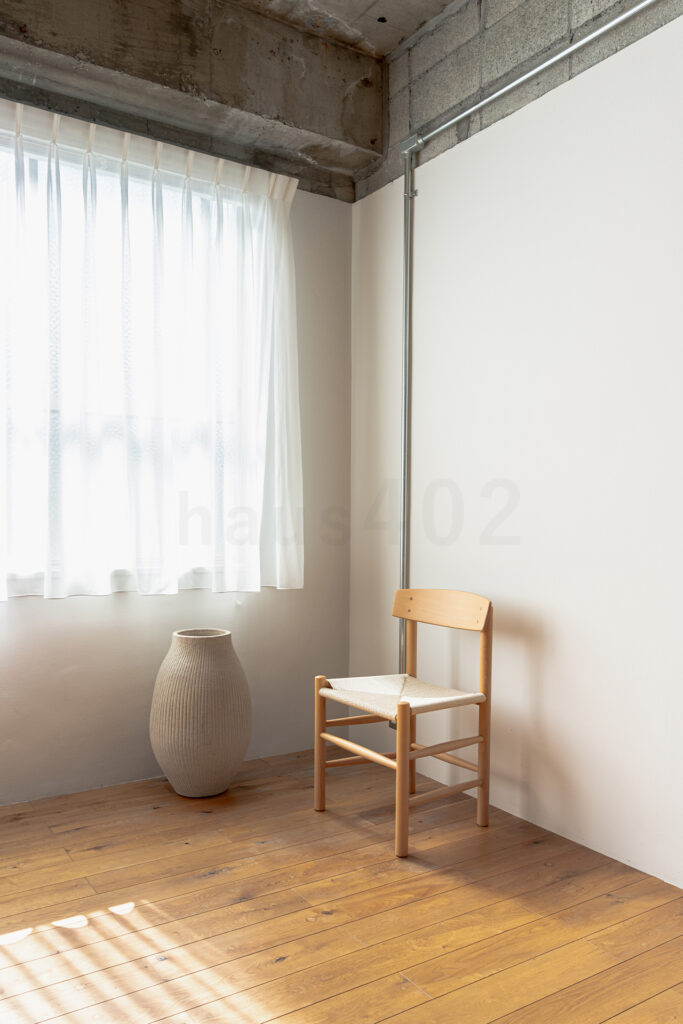 株式会社ラズスタジオの自社スタジオ「haus402」の無垢材床の空間でチェアとオブジェを配置した写真