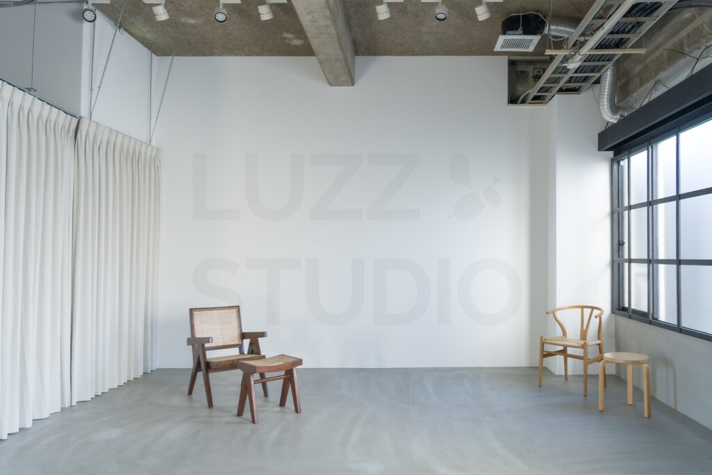 アパレルやインテリア雑貨のカタログ撮影に最適な大阪のスタジオ。モルタルグレー床に上質なヴィンテージ家具と広い白背景が調和した、静謐なクリエイティブ空間