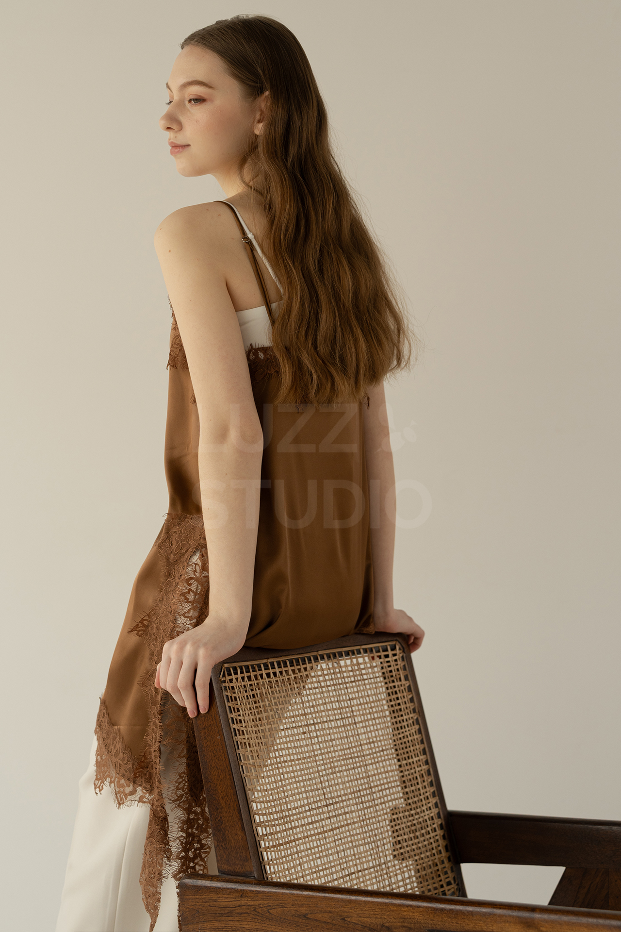 椅子の背もたれに腰かけているレディスモデルの後ろ姿のアパレルモデル撮影