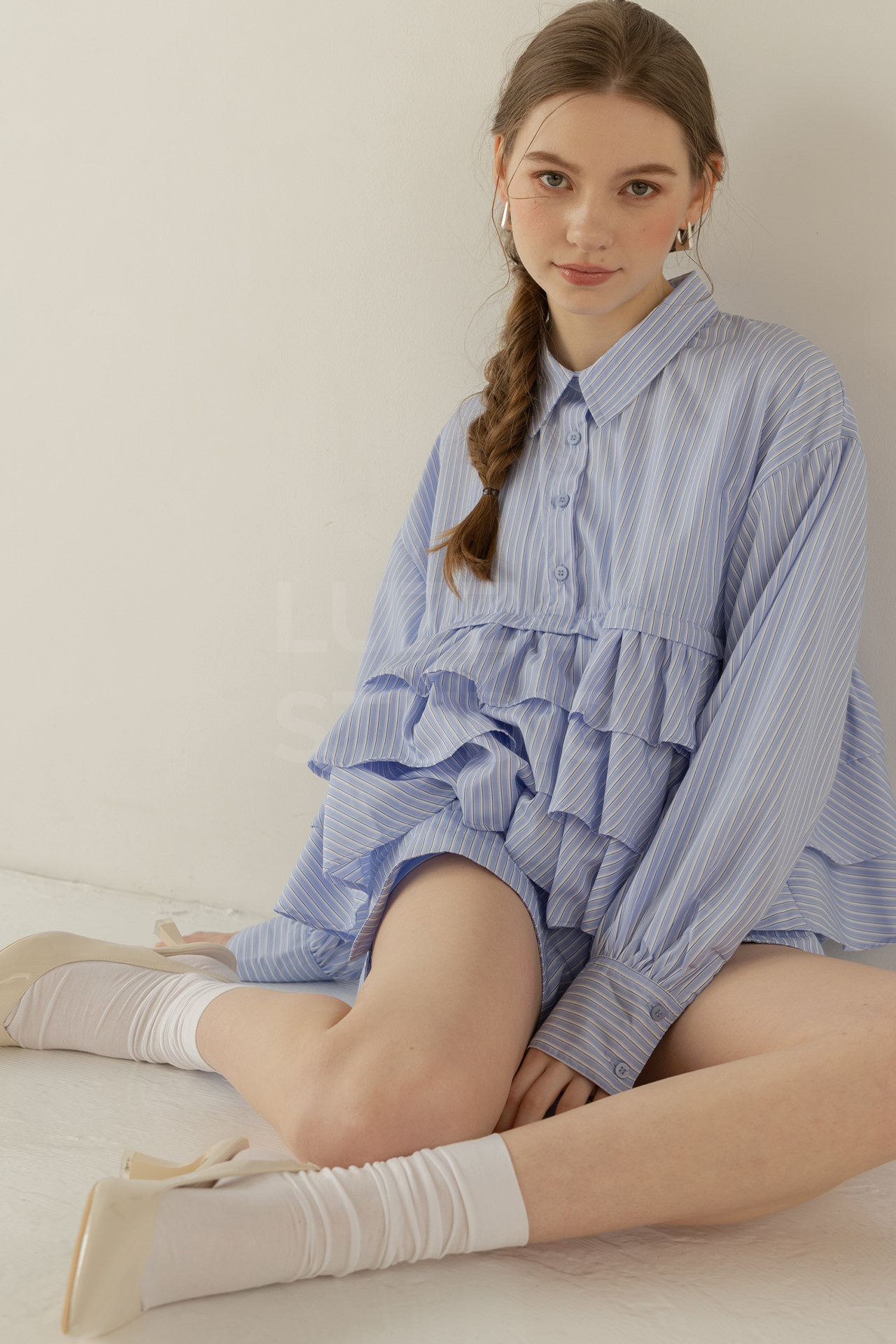 白壁白床に座り込む女性モデルのアパレル撮影写真