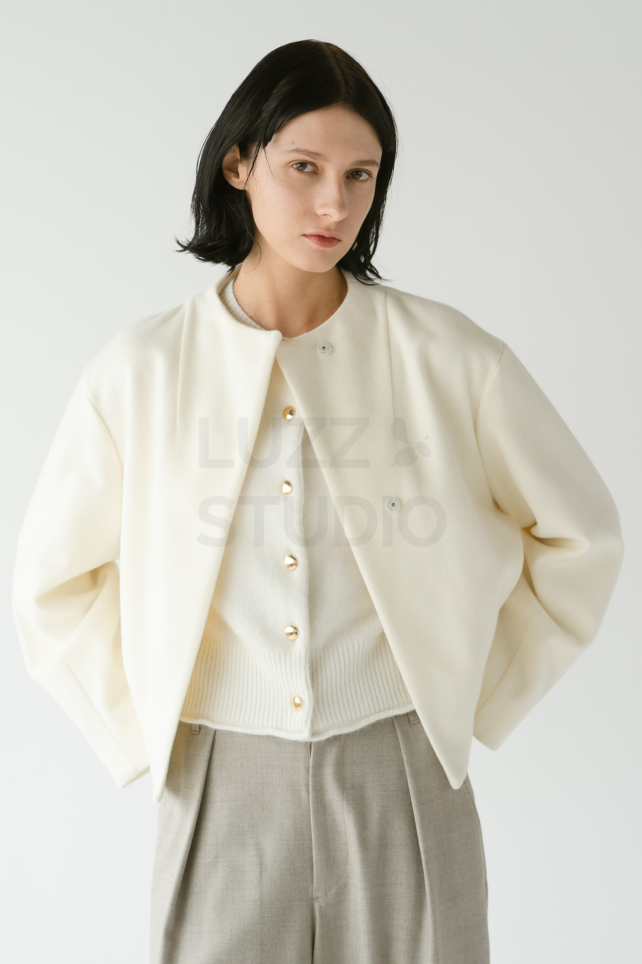 白いノーカラージャケットに同系色のインナー、グレーのワイドパンツを着用したモデルのバストアップ写真