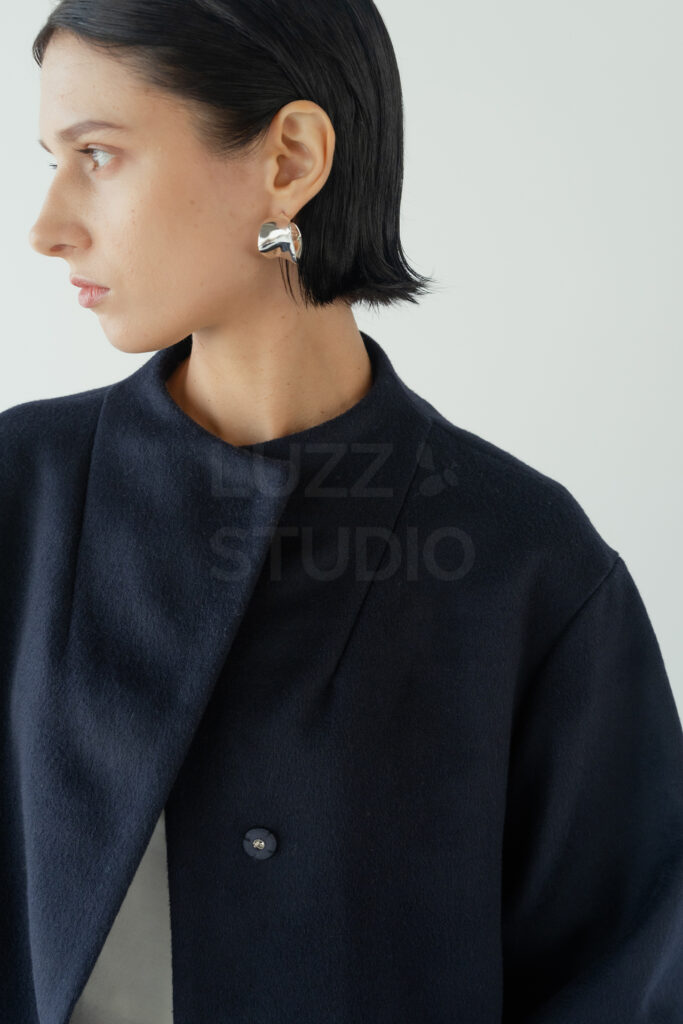 深いネイビーのコートの襟元と、モデルの横顔の美しいシルエットをクローズアップで捉えたビューティーカット